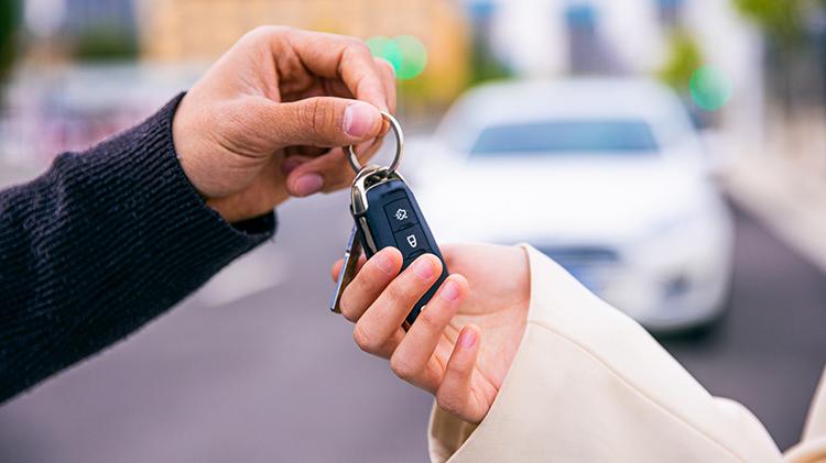 Man passing car keys to a woman.